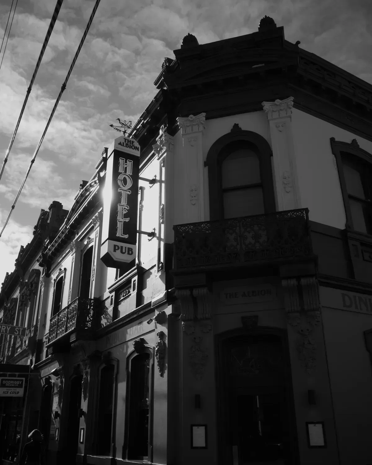 The Albion, a corner pub with an ornate facade and a vertical hotel pub sign, under a cloudy sky.